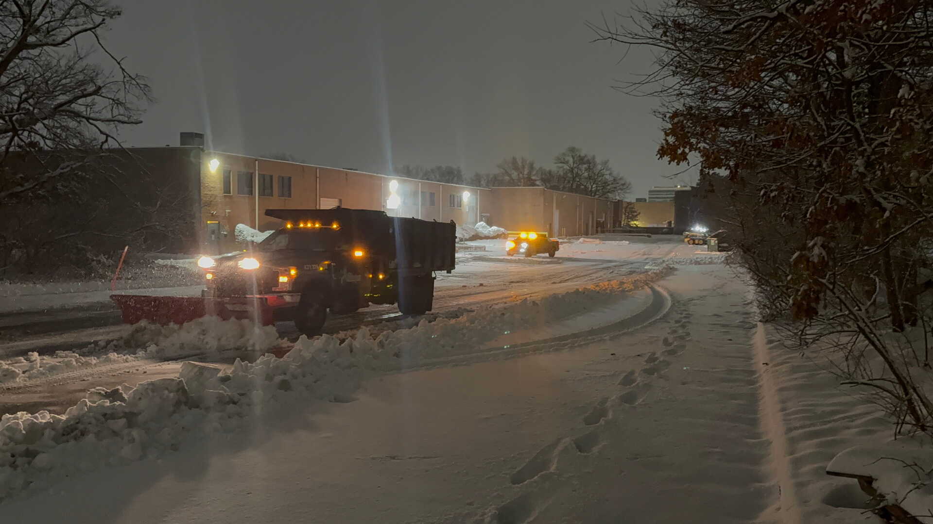 Picture of a reinigen lawns plow truck and skid steer clearing snow from a commercial warehouse